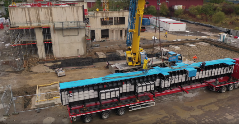 Prefabricated service pit being lowered by crane on site