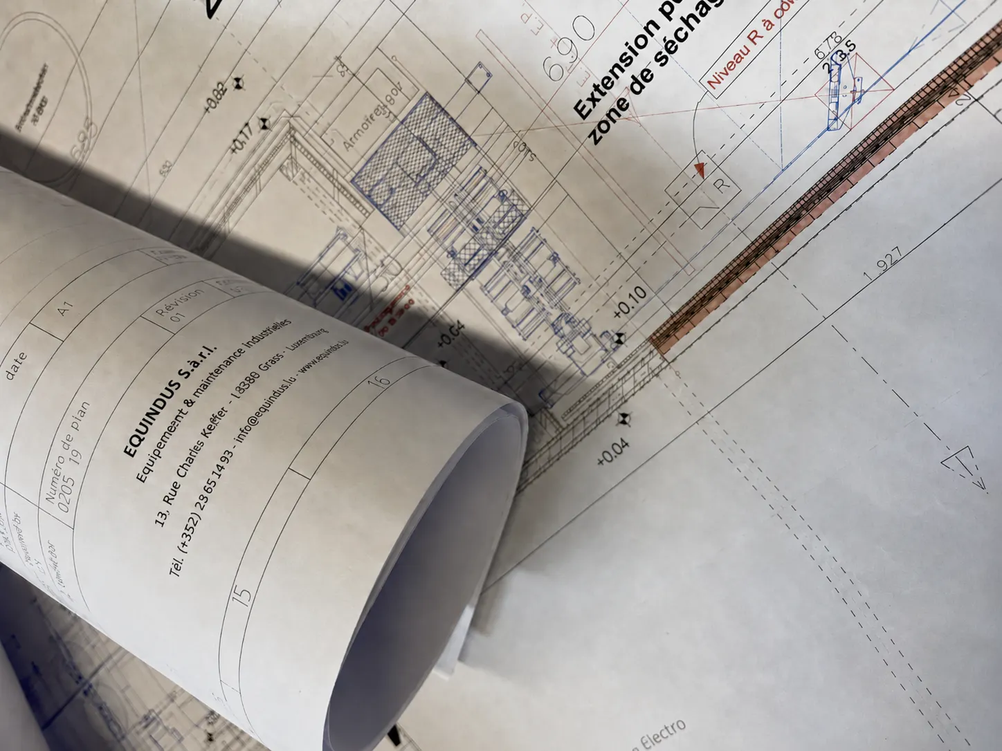 Rolled workshop layout drawings on a worktop, Equindus design office in Grass