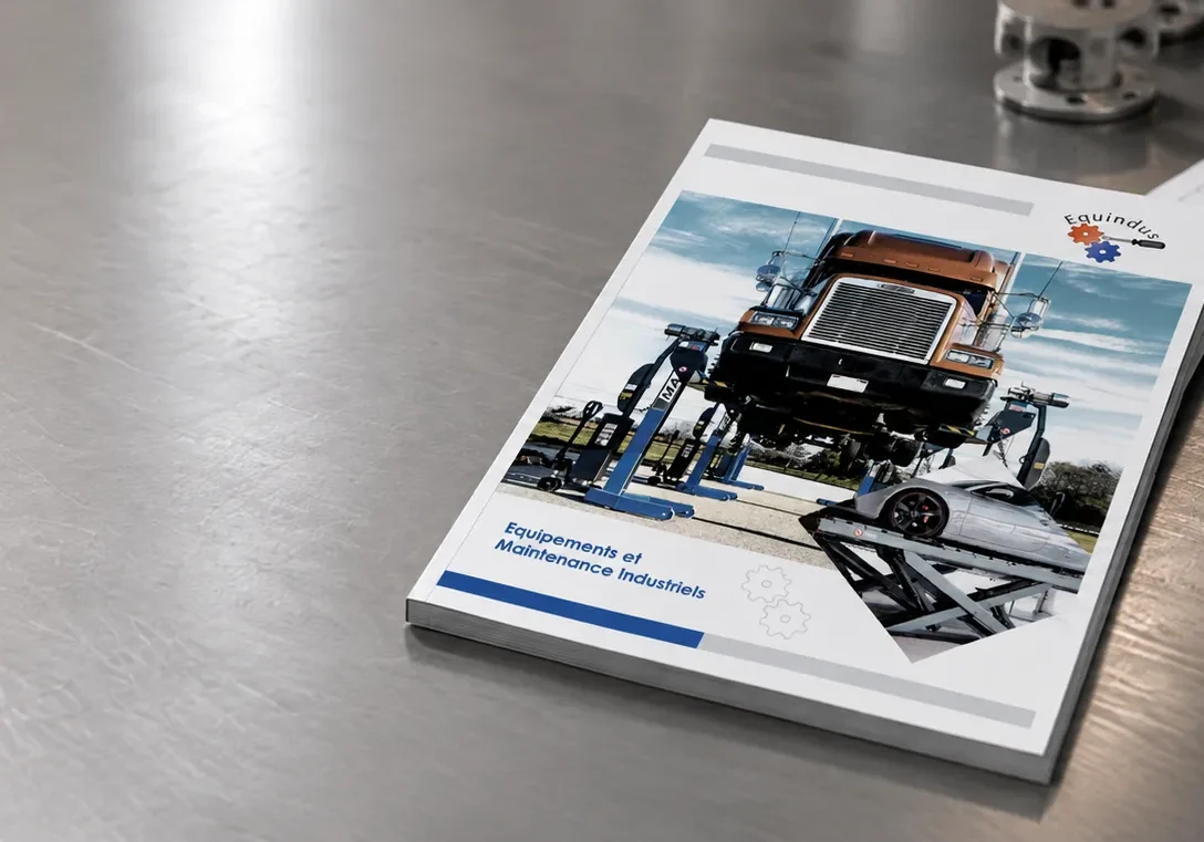 Catalogue Equindus présentant des équipements de levage et de maintenance industriels, posé sur un établi métallique